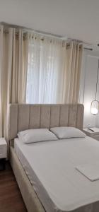 1 dormitorio con 1 cama blanca grande y cortinas blancas en Heart of Tirana Apartment, en Tirana