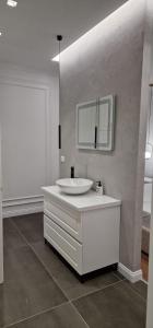 a white bathroom with a sink and a mirror at Heart of Tirana Apartment in Tirana