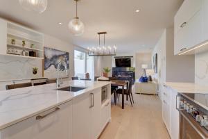 a kitchen with white cabinets and a dining room at Ripplecove Hotel & Spa in Ayer's Cliff