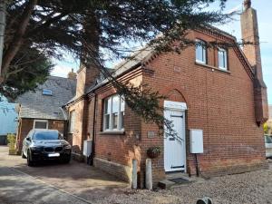 a brick house with a car parked in front of it at 3 The Old Schoolhouse: hot tub, log burner, parking, en-suite in Whitstable