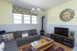 a living room with a couch and a flat screen tv at 3 The Old Schoolhouse: hot tub, log burner, parking, en-suite in Whitstable