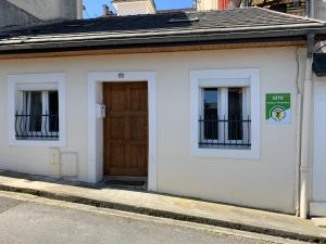 un pequeño edificio blanco con puerta de madera en BASIA, Lourdes - centre , quartier historique Sanctuaires a 7 min a pied, en Lourdes