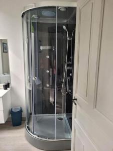- une douche en verre dans une salle de bains située à côté d'une porte dans l'établissement Maison Cosy en bord de rivière, à Bort-les-Orgues