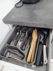 un cajón lleno de utensilios de cocina bajo un mostrador en Maison Cosy en bord de rivière, en Bort-les-Orgues