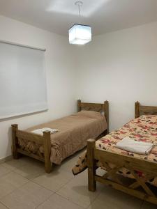 two beds sitting in a room with a white wall at Casa Balcarce Mendoza in Guaymallen
