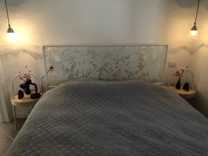um quarto com uma cama com colcha cinzenta e candeeiros em Casa ESTELLA em Magliolo
