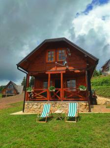 dos sillas sentadas frente a una cabaña de madera en Tarovuk cabin en Zaovine