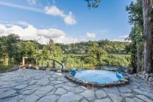 un patio de piedra con bañera de hidromasaje junto a un río en Splendid Arroyo Frio 4BR Rustic Villa, en Constanza