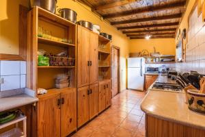 cocina con armarios de madera y nevera en Splendid Arroyo Frio 4BR Rustic Villa, en Constanza