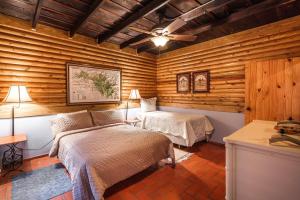 1 dormitorio con 2 camas en una habitación con paredes de madera en Splendid Arroyo Frio 4BR Rustic Villa, en Constanza