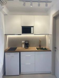 eine Küche mit weißen Schränken, einer Spüle und einer Mikrowelle in der Unterkunft Serafina suite byArtistUnknown in Vari