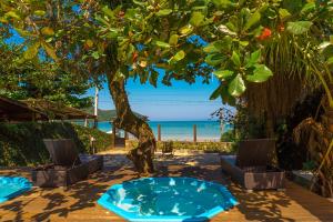 uma árvore com duas cadeiras e uma banheira de hidromassagem na praia em Pousada Vila Jacaa em Ubatuba