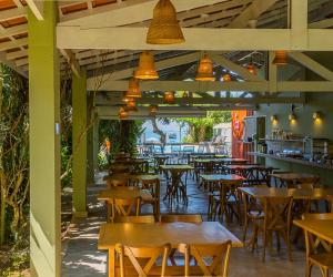 um restaurante vazio com mesas e cadeiras de madeira em Pousada Vila Jacaa em Ubatuba