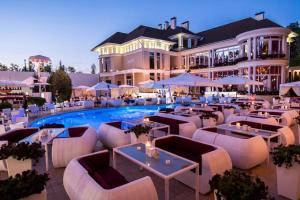 a hotel with tables and chairs in front of a pool at Гостевой Дом у Моря, Guest House by the Sea in Odesa