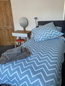 a bed with a blue and white comforter and a desk at Comfortable 2 bedroom home from home with parking in Nottingham