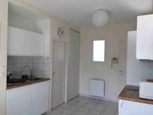 uma cozinha com armários brancos e uma janela em « Les 3 Hirondelles » près des Antilles de Jonzac em Jonzac