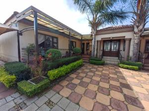 a house with a patio and palm trees at Leondale Guest House in Germiston