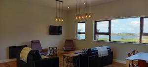 a living room with two chairs and a table and windows at Murrisk Apartments - Self Catering in Westport