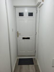 a white door in a white hallway with a rug at Delight Apartment, Close to Excel, London City Airport & O2! in London