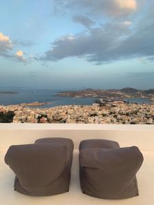 zwei Stühle vor einem Blick auf die Stadt in der Unterkunft ArtdecoSyros Superior in Ano Syros