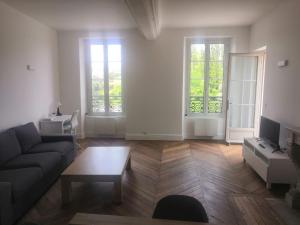 sala de estar con sofá y 2 ventanas en Grand 2P Terrasse bord de seine, en Mantes-la-Jolie