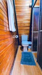 een kleine badkamer met een toilet in een houten muur bij Shizen hospedaje, eventos y camping 
