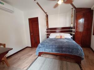 1 dormitorio con 1 cama y ventilador de techo en The Wooden House Hotel, en Puerto Villamil