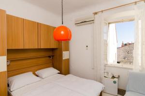 a small bedroom with a bed and an orange lamp at Rooms Pile in Dubrovnik