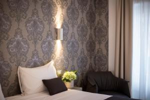 1 dormitorio con cama, silla y papel pintado en Hotel Ponti, en Angera