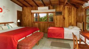 1 dormitorio con 2 camas, escritorio y ventana en The Wooden House Hotel, en Puerto Villamil