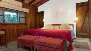 Un dormitorio con una cama con sábanas rojas y una ventana en The Wooden House Hotel, en Puerto Villamil