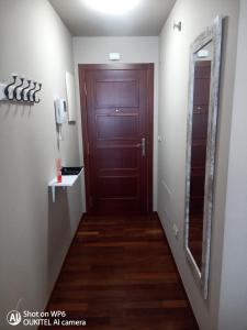 a hallway with a brown door and a mirror at Suite XIMENA con piscina in Viveiro