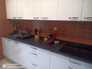 a kitchen with white cabinets and a black counter top at Suite XIMENA con piscina in Viveiro