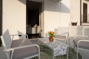 a porch with white chairs and a table with a vase of flowers at suite la corte in Sannicandro di Bari