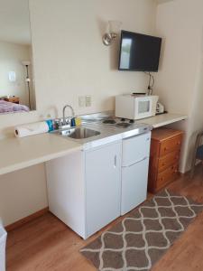 a small kitchen with a sink and a microwave at The Dublin House Motel in Yachats