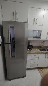una nevera de acero inoxidable en una cocina con armarios blancos en Apartamento ótimo padrão volta redonda en Volta Redonda