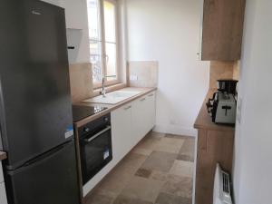 eine Küche mit einem schwarzen Kühlschrank und einer Spüle in der Unterkunft Grand 2P Terrasse bord de seine in Mantes-la-Jolie