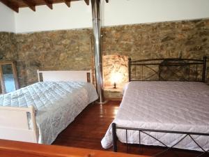 a bedroom with two beds and a stone wall at ΑΝΑΒΑΤΟΣ ΕΞΟΧΙΚΗ ΚΑΤΟΙΚΙΑ in Chios
