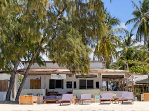 una casa en la playa con sillas y palmeras en Meraki - Cafe Bar Rooms, en Paje