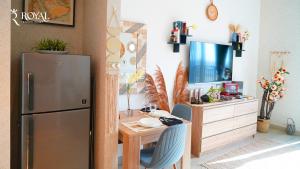 a kitchen with a refrigerator and a table with a tv at Boho Chic Studio Apartment on Yas with Pool Access in Abu Dhabi