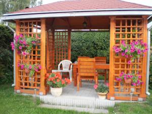 a wooden gazebo with a table and chairs and flowers at Apartmán Orlík nad Vltavou in Orlík