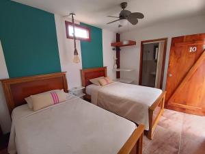 2 camas en una habitación con paredes verdes y blancas en The Wooden House Hotel, en Puerto Villamil