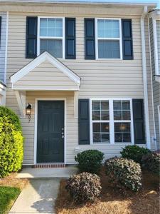 uma casa branca com uma porta preta e alguns arbustos em Stylish, Cozy Corporate Townhome with Pool! em Greensboro