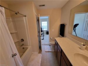 a bathroom with a tub and a sink and a mirror at Stylish, Cozy Corporate Townhome with Pool! in Greensboro