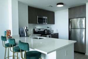 a kitchen with a white counter and green chairs at Luxury 2'2 apartment brickell downtown in Miami
