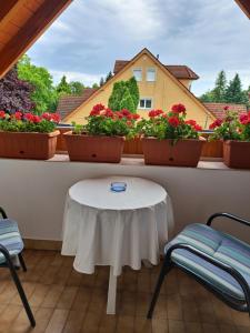 a white table and chairs on a balcony with flowers at EMMA Apartman Harkány in Harkány