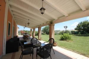 un patio con mesa y sillas en un porche en Villa Diana - Pesaro mare e cultura - intera struttura con piscina, en Mombaroccio