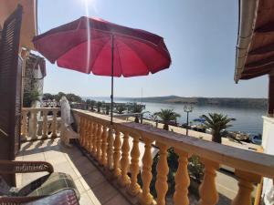 a red umbrella on a balcony with a view of the water at Apartmani More in Posedarje