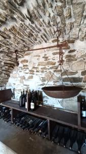 Casa Vacanza Contado Latino في Belmonte del Sannio: غرفة بجدار حجري مع طاولة مع زجاجات النبيذ