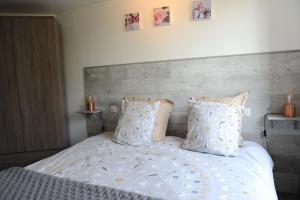 ein Bett mit weißer Bettwäsche und Kissen in einem Schlafzimmer in der Unterkunft Gîte l'ancienne forge 4 adultes et 2 enfants in Louvetot